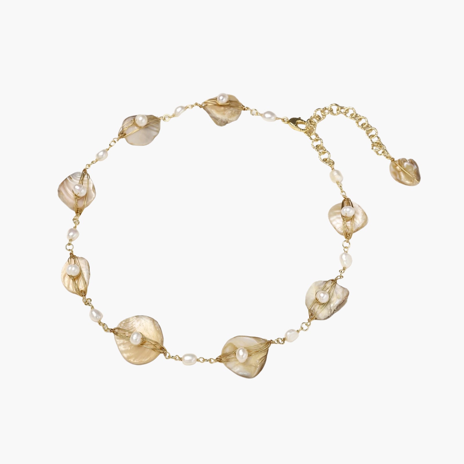 Gold-plated necklace with wire-wrapped shell pieces and freshwater pearls on neutral background, adjustable chain visible.