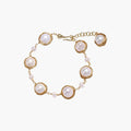 Gold wire-wrapped freshwater pearl bracelet with alternating pearl sizes on cream background, adjustable length