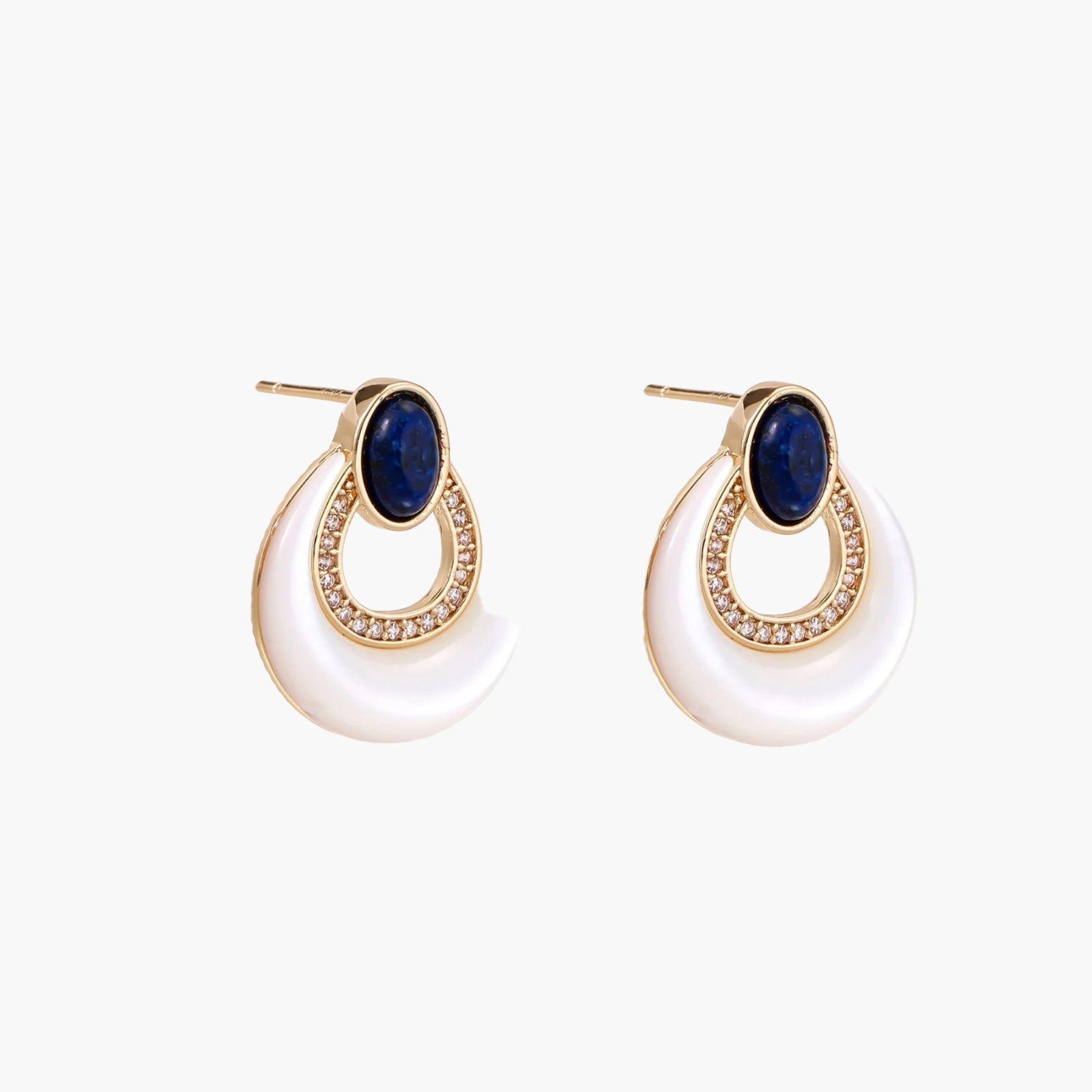 Gold drop earrings with oval lapis lazuli, crystal-paved frame, and iridescent mother-of-pearl teardrop on cream background