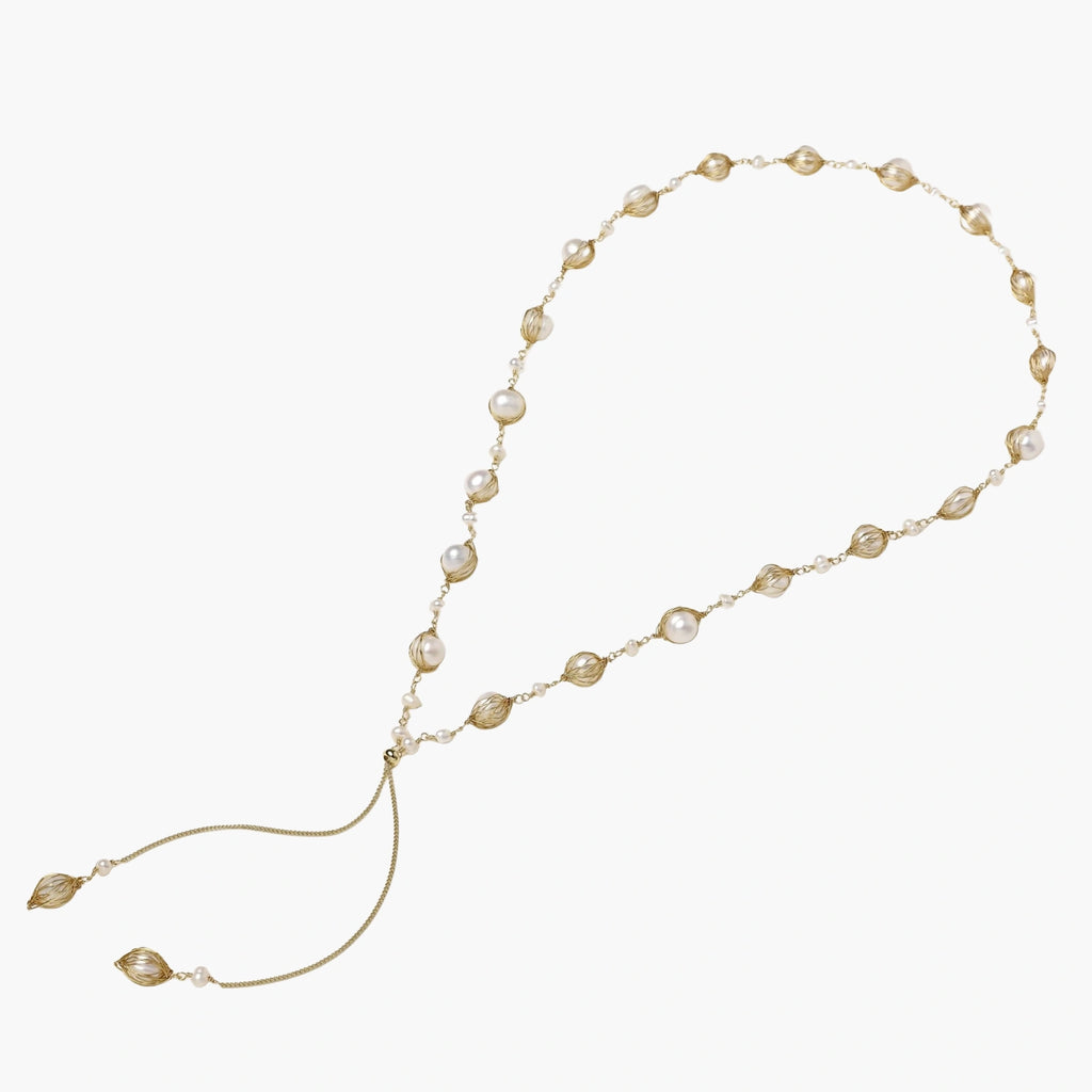 Adjustable gold lariat necklace with freshwater pearls nested in delicate cage settings and Y-shaped tassel drop
