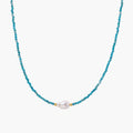 Delicate gold vermeil necklace with teal apatite beads and freshwater pearl on white background.