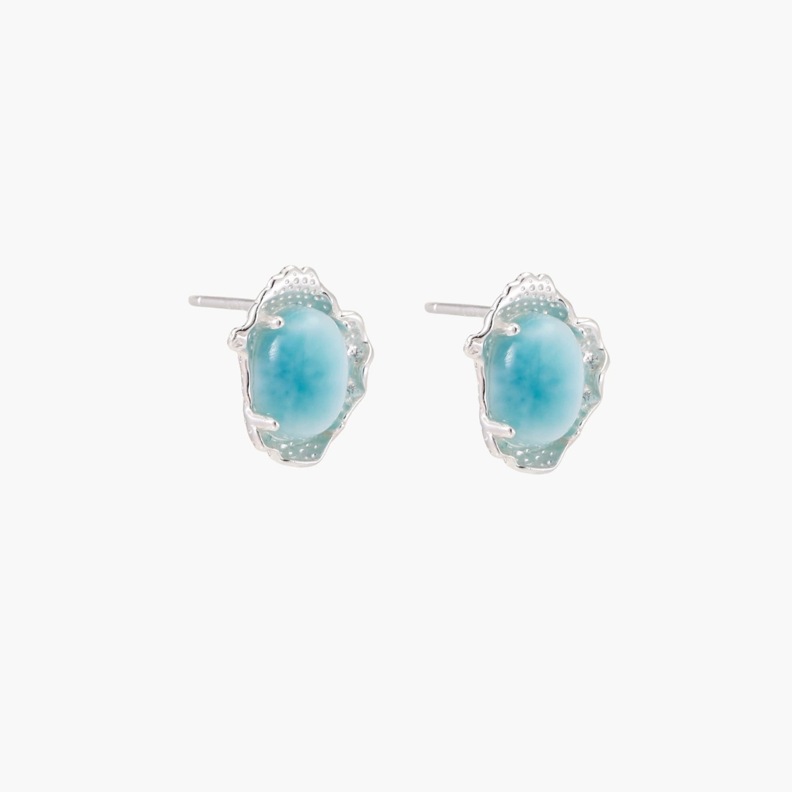 Oval larimar gemstone studs with ornate silver settings showing natural turquoise marbling on cream background