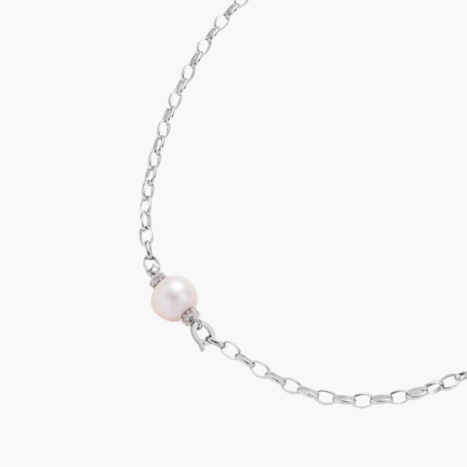Dainty rhodium-plated silver chain necklace with centered 10mm freshwater pearl and crystal accents on cream background