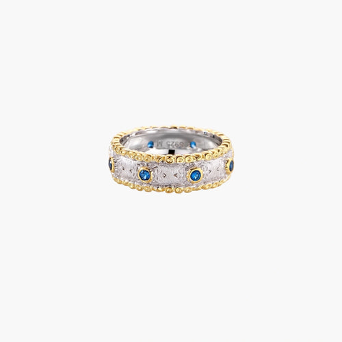 Two-tone ring with brushed silver center, gold beaded edges, and blue zirconia stones on white background.