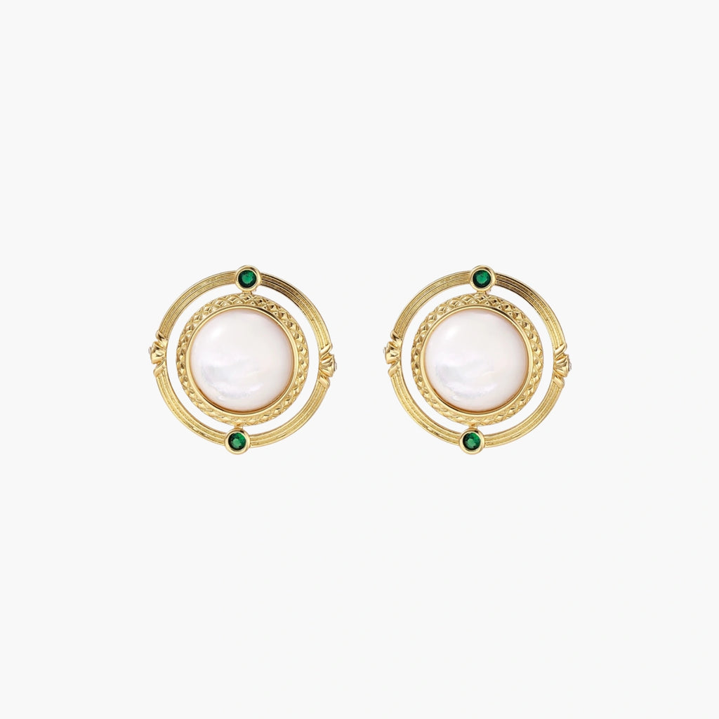 Circular gold stud earrings with iridescent mother-of-pearl center and green zirconia accents on cream background.