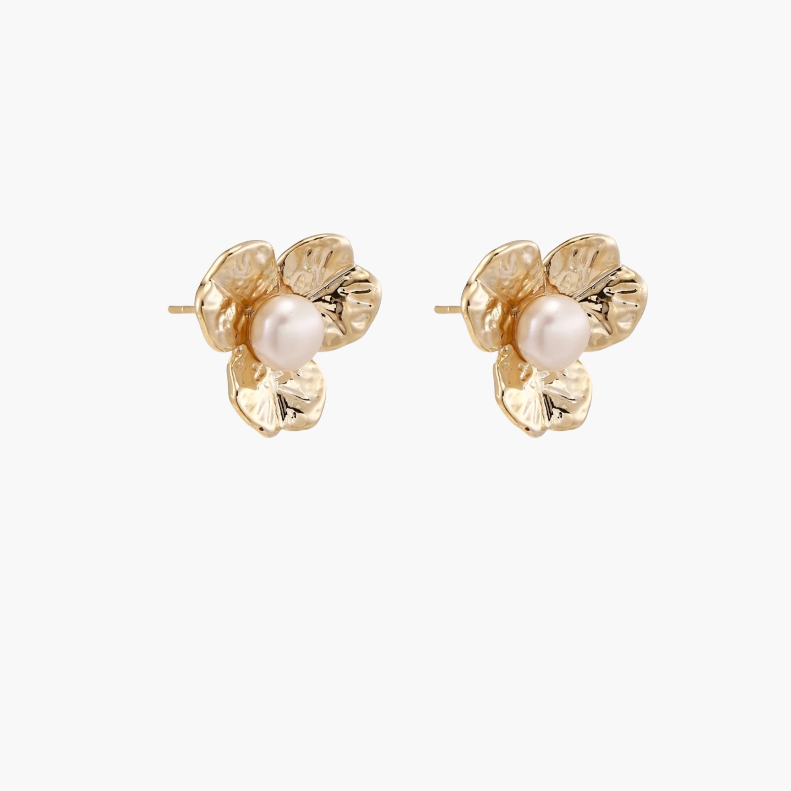 Gold-plated flower stud earrings with textured petals and centered freshwater pearl on beige background