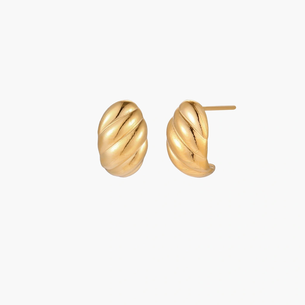 Chunky gold twisted rope huggie hoops with diagonal grooves and high-polish finish on cream background