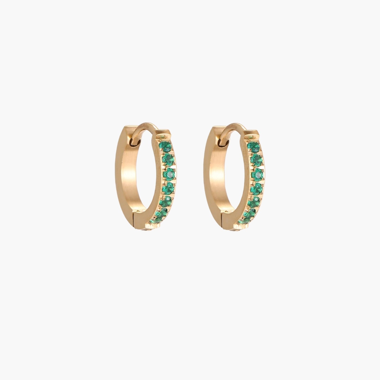 Pair of small gold huggie hoop earrings with bright green cubic zirconia stones on cream background